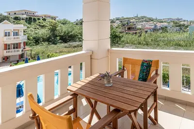 a wooden table and chairs on a balcony at Artemis Apartments in Stalos