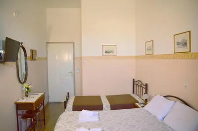 a bedroom with two beds and a table and a mirror at Stoa Rooms in Chania Town
