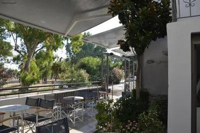 a patio with tables and chairs under a white canopy at Kiwi Apartments in Kato Daratso