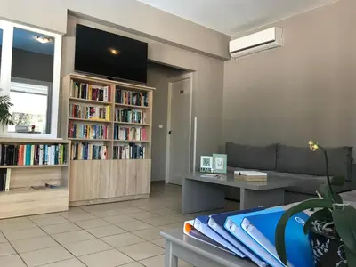 a living room with a couch and a book shelf filled with books at Kiwi Apartments in Kato Daratso