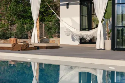 a swimming pool with a hammock next to a house at San Pietro Villa in Plataniás