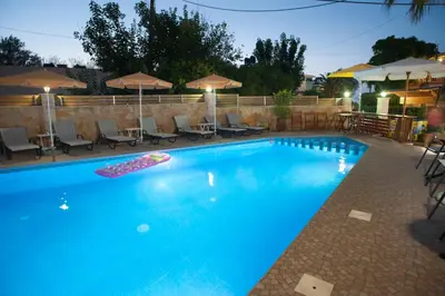 a large blue swimming pool with chairs and umbrellas at Nikolas Suites in Kato Daratso