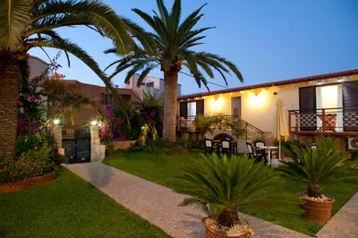 a courtyard with palm trees and a house at Nikolas Suites in Kato Daratso