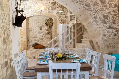 a dining room with a table and white chairs at Trigono Luxury House in Kissamos