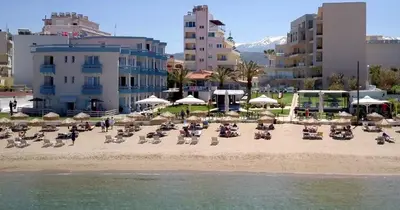 a sandy beach with chairs and umbrellas and buildings at Hotel Christina in Chania Town