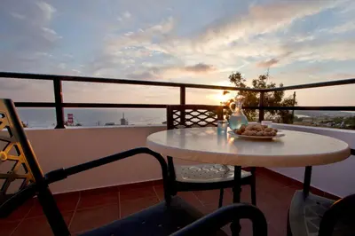 a table with a bowl of fruit on a balcony at Nikos Apartments in Falasarna