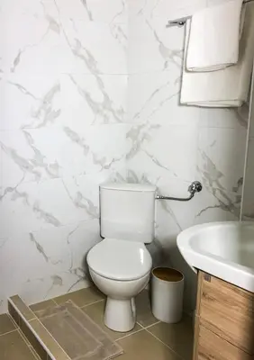 a white bathroom with a toilet and a sink at Stelisia Rooms in Chania Town