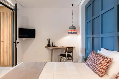 a bedroom with a bed and a table with a chair at Blue Island Luxury Apartment in Kato Daratso