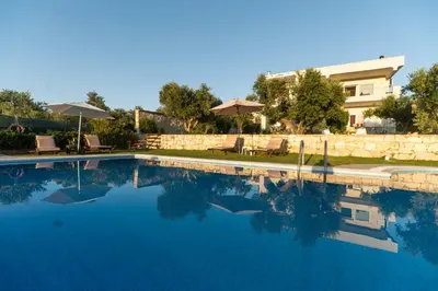 a swimming pool with blue water in front of a house at Rodanthi Villas in Darmarochori