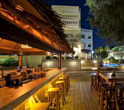 a bar with wooden tables and chairs at night at Aphrodite Beach in Kissamos