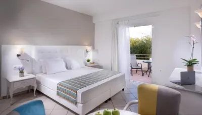 a white bedroom with a bed and a balcony at Dore Boutique Hotel in Agia Marina Nea Kydonias