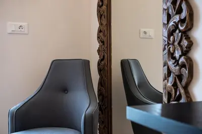 a mirror and a black chair in front of a table at Avra Apartments Kolymbari Harbour in Kolymvari