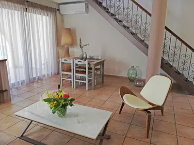 a living room with a table and chairs and a staircase at Althea Maisonettes in Áptera