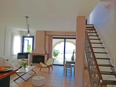 a living room with a staircase and a table and chairs at Althea Maisonettes in Áptera