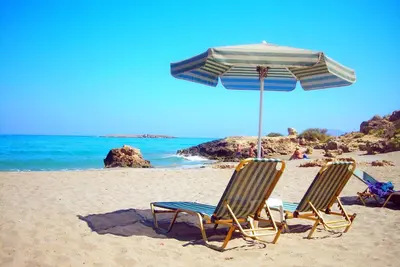 two chairs and an umbrella on a beach at Aptera Beach Apartment in Kato Daratso