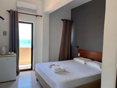 a bedroom with a bed with a view of the beach at Kalami Rooms in Falasarna