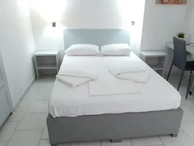 a bed with white sheets and pillows in a room at Diana Rooms in Chania Town