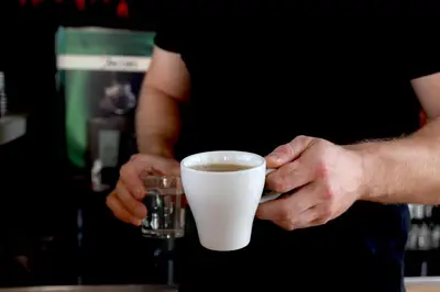a man holding a cup of coffee and a glass at Pegasus Hotel in Stalos