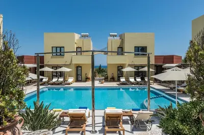 a swimming pool with chairs and umbrellas in front of a building at Daphnis Villas in Maleme