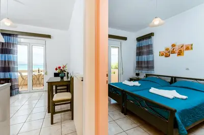 a bedroom with a blue bed and a balcony at Asterina Seaside Apartments in Kalyves