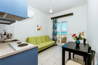 a kitchen and a living room with a yellow couch at Asterina Seaside Apartments in Kalyves