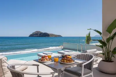 a dining room with a table and chairs and the ocean at Marika Beach Hotel in Plataniás