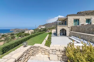 a house with a stone wall and a walkway at Aspalathos Falassarna Villas in Falasarna