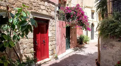 a red door on the side of a building with flowers at Fougaro Apartments in Chania Town