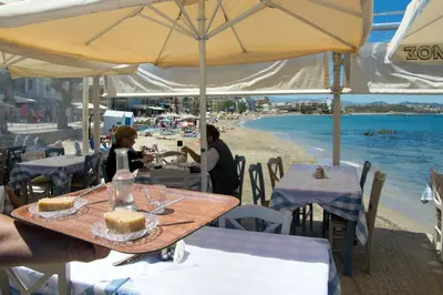 a person holding a tray with a piece of cake on a table on the beach at Fougaro Apartments in Chania Town