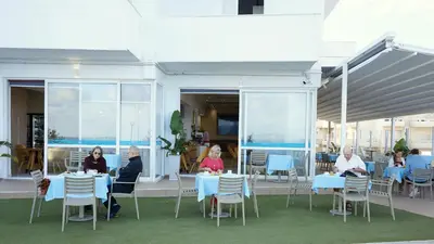 a group of people sitting at tables in a restaurant at Klinakis Beach Hotel in Chania Town