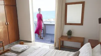 a woman standing in a room looking at the ocean at Klinakis Beach Hotel in Chania Town