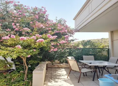 a patio with pink flowers and a table and chairs at Marianna Apartments in Almirida