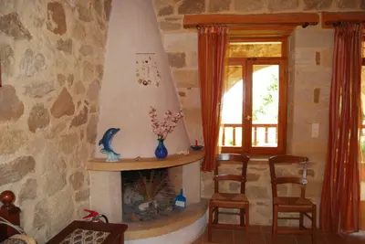 a living room with a fireplace with two chairs and a window at Golden Sun Apartments in Falasarna