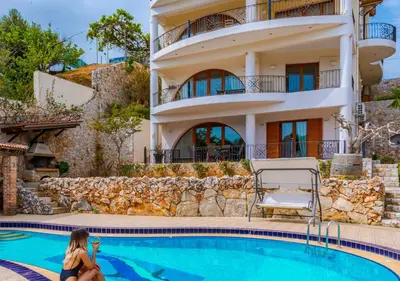 a woman sitting next to a swimming pool in front of a house at Zen Serenity Retreat with Great Outdoors, Pool & Parking in Áptera