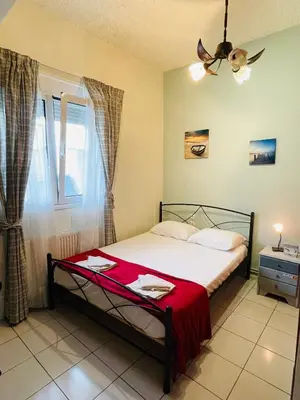 a bedroom with a bed with a red blanket at Nea Chora cozy apartment close to the beach in Chania Town