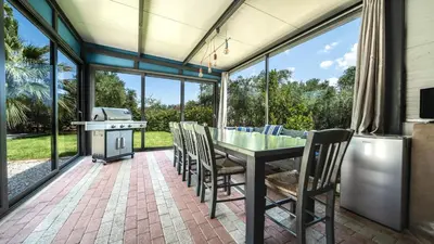 a screened in porch with a table and chairs and a grill at Petronila Luxury Villa with heated private pool in Kissamos