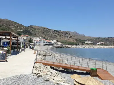 a bench on a beach next to the water at Gina's home in Kolymvari
