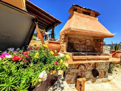 an outdoor oven with flowers in front of a house at Thymes traditional house in Loúlos