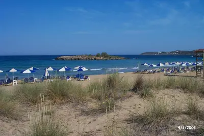 a beach with chairs and umbrellas and the ocean at Comfortable House near Chania in Kalathas