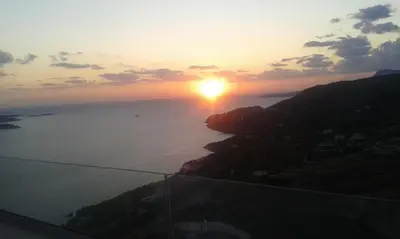a sunset over the ocean with the sun setting on a hill at PALACE Sea view in Megála Khoráfia