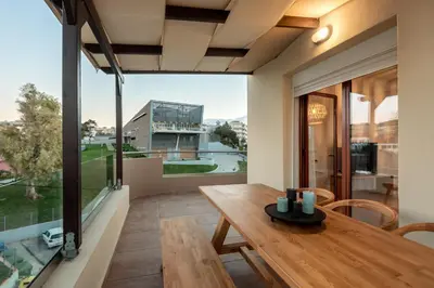 a dining room with a wooden table and a large window at Soleado apartment in Chania Town