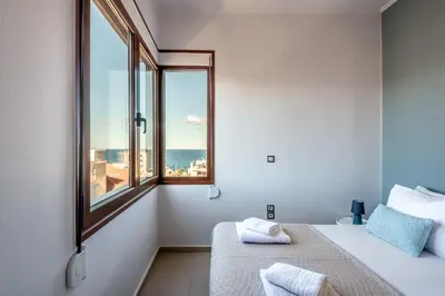 a bedroom with two beds and a large window at Soleado apartment in Chania Town