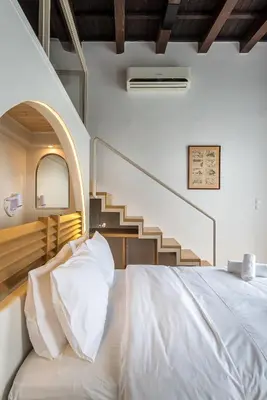 a bedroom with a white bed with a staircase at Hotel Amphora in Chania Town