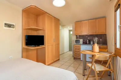 a bedroom with a bed and a table and a kitchen at Lidra Rooms in Chania Town
