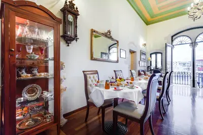 a dining room with a table with chairs and a clock at Casa Leone Hotel in Chania Town