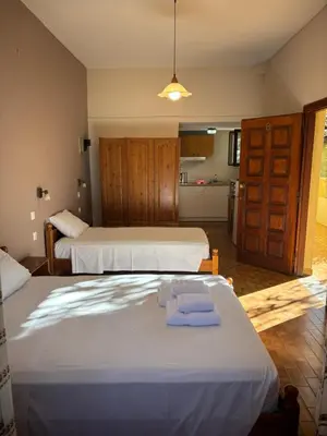 a bedroom with two beds and a kitchen in the background at Stelios Rooms in Palaiochóra