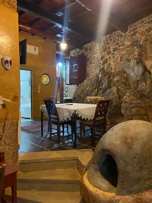a dining room with a table and a stone wall at Ifigenia Theriso Village in Thérison