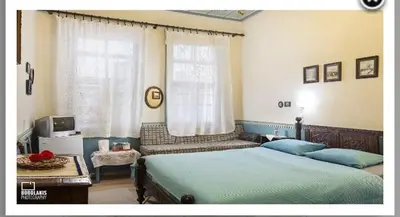 a bedroom with two beds and a tv and a window at Pension Lena in Chania Town