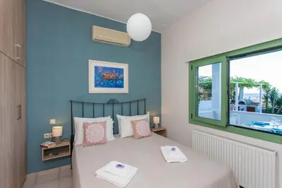a bedroom with a bed with pink pillows and a window at Chania Sea View Summer House in Kalamaki Chanion