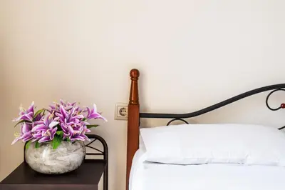 a vase of purple flowers on a table next to a bed at Marelen Apartment Near Chania Center in Chania Town